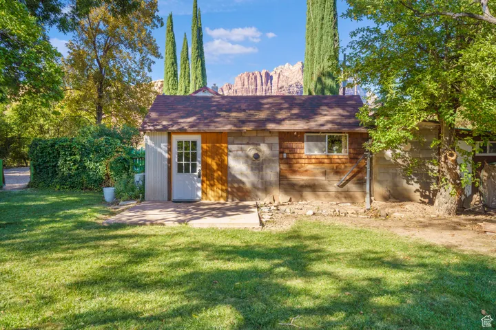 Rear view of property featuring a yard, a patio area, and an outdoor structure