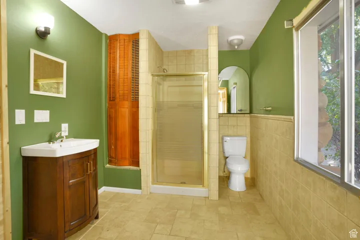 Bathroom with vanity, a stall shower, and tile walls