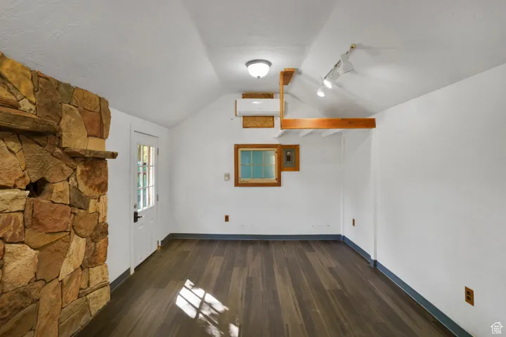 Bonus room with vaulted ceiling, dark wood-style floors, a textured ceiling, and a wall mounted air conditioner