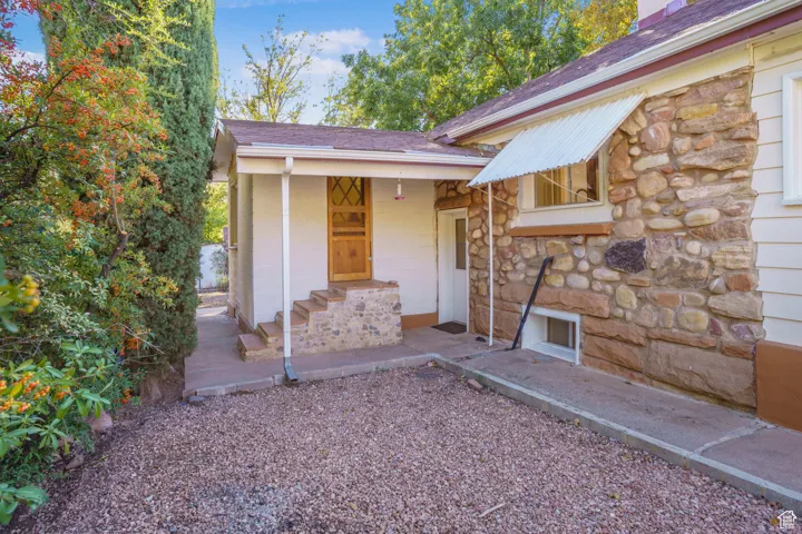 Property entrance with stone siding and a shingled roof