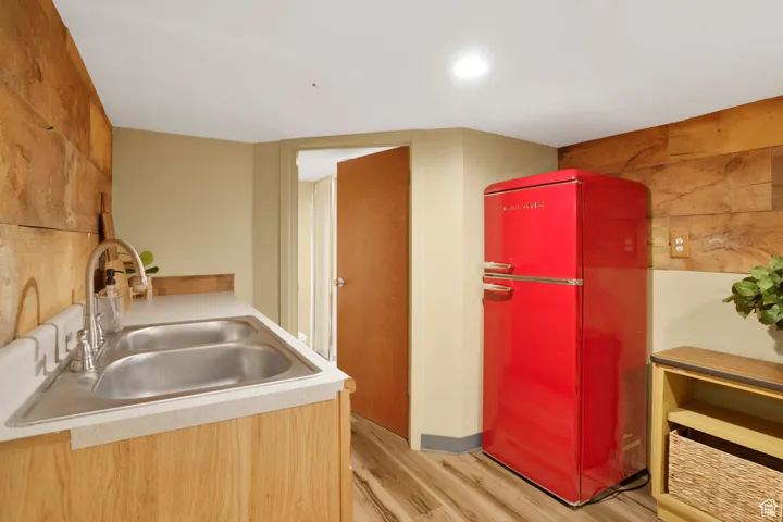 Kitchen with freestanding refrigerator, light wood finished floors, light brown cabinets, and light countertops
