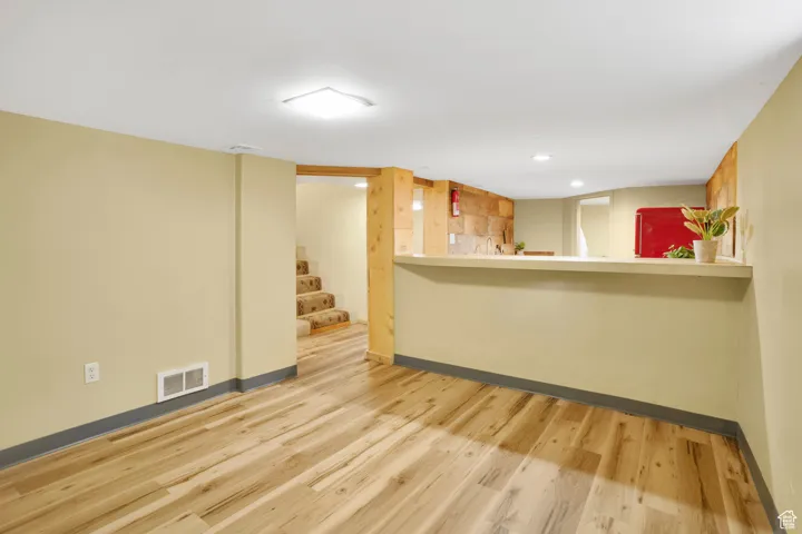 Bar featuring light wood-style floors, light countertops, and stairs