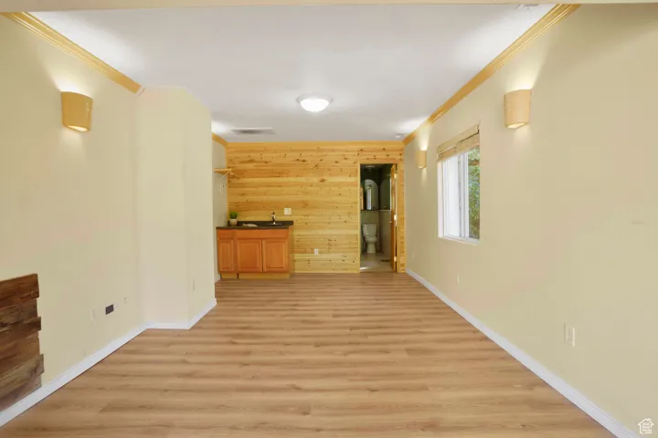 Corridor featuring wooden walls, ornamental molding, and light wood-style floors