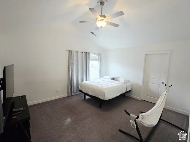 Bedroom featuring dark colored carpet, ceiling fan, and high vaulted ceiling