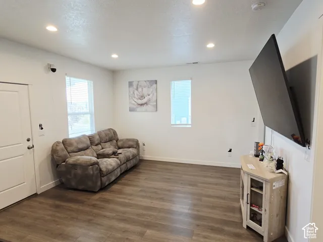 Living room with dark wood-type flooring, recessed lighting, and a textured ceiling
