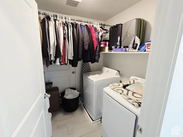 Laundry area with light tile patterned floors and washing machine and clothes dryer