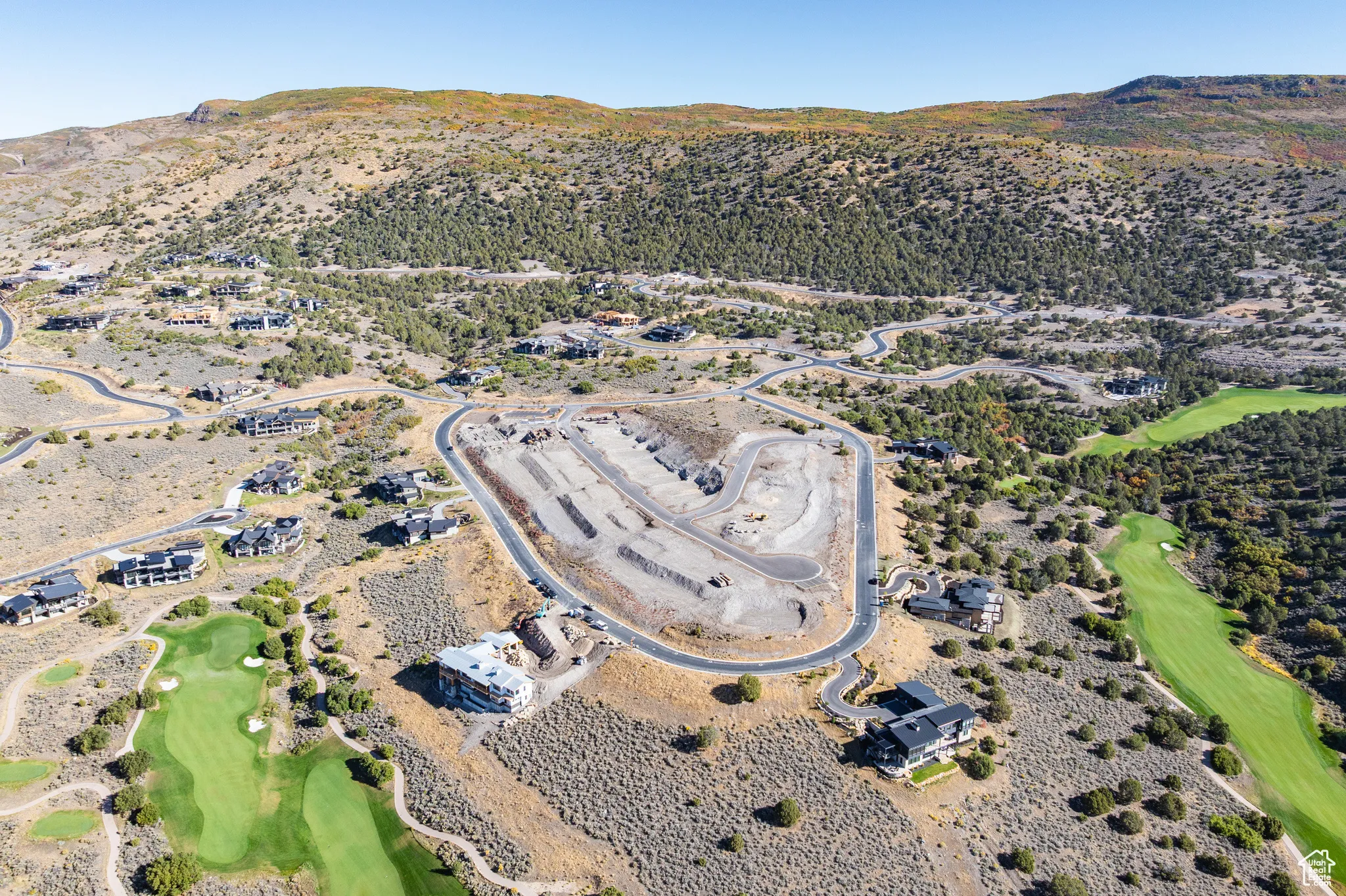 Aerial view of property's location featuring a mountainous background and a local golf course
