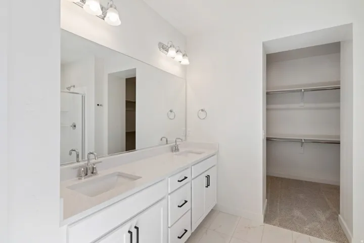 Bathroom with a spacious closet, a stall shower, double vanity, and light marble finish floors