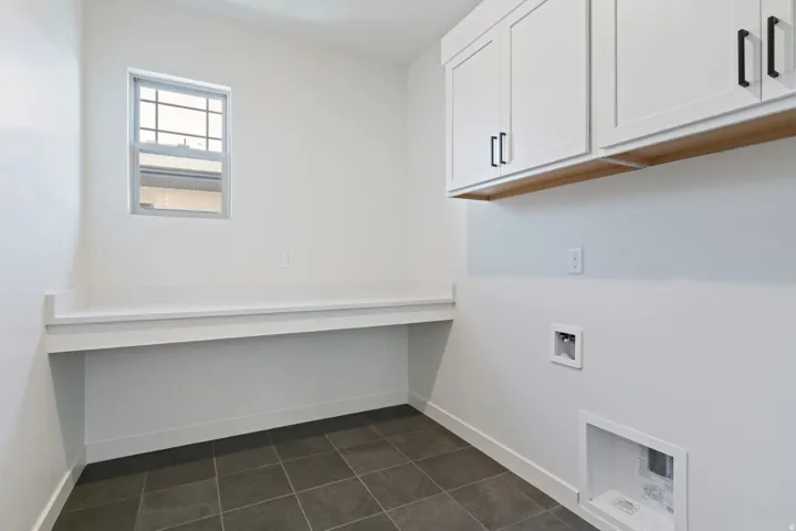 Laundry room with cabinet space, washer hookup, and dark tile patterned flooring