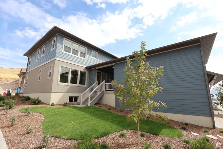 Rear view of property featuring a yard and stairway