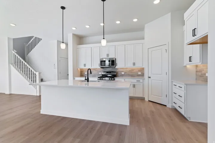 Kitchen with white cabinetry, a kitchen island with sink, decorative backsplash, and recessed lighting