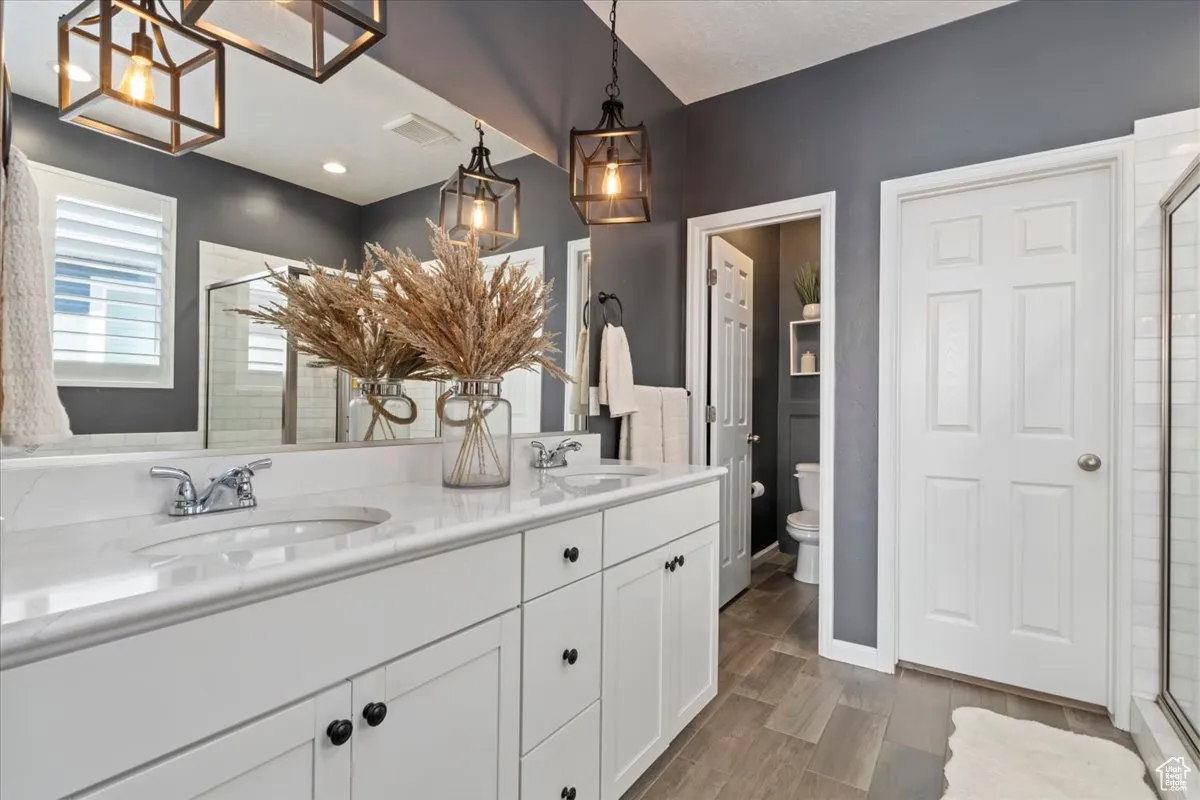Bathroom with a shower stall, double vanity, and wood tiled floors