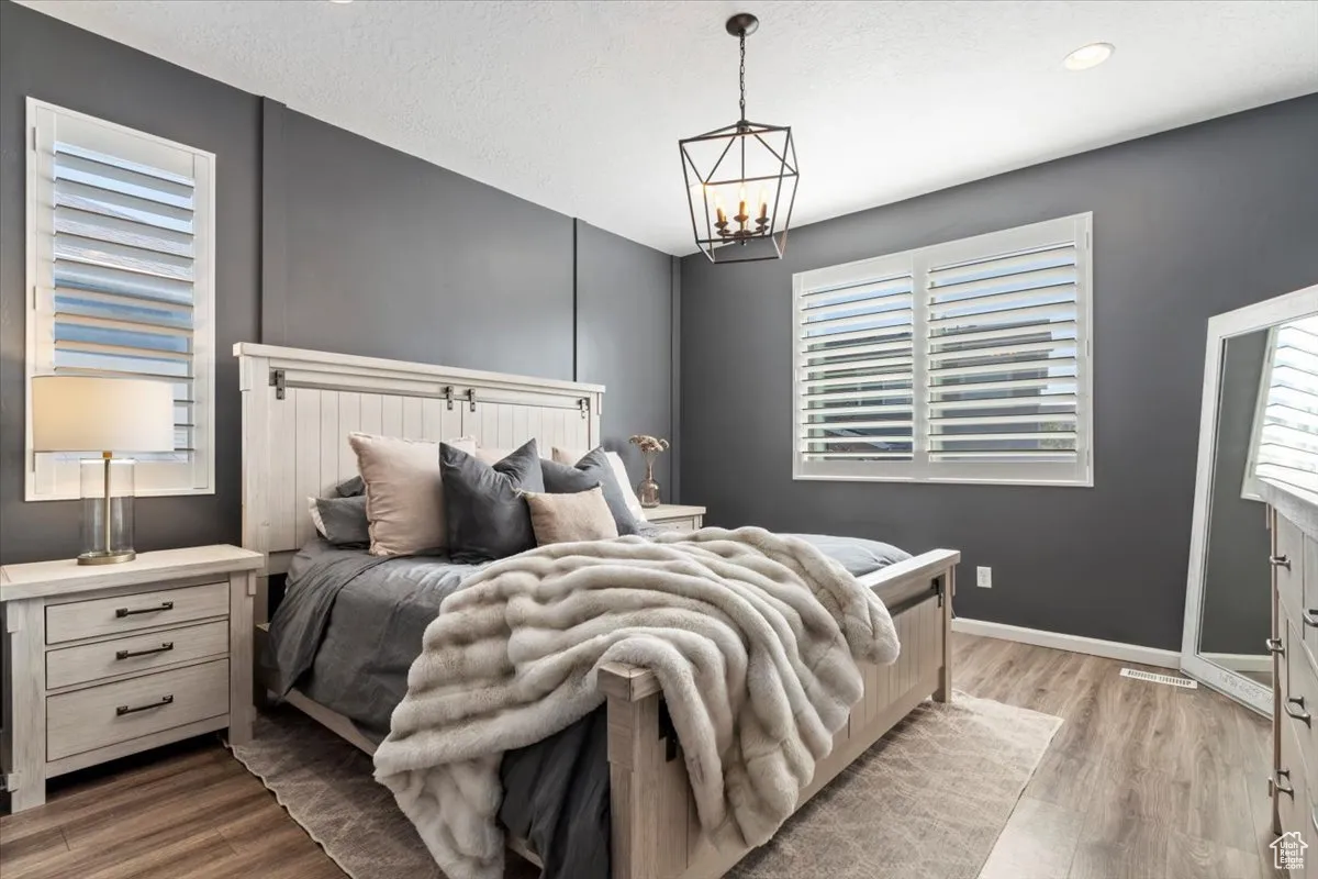 Bedroom with multiple windows, light wood-style floors, a textured ceiling, and a chandelier