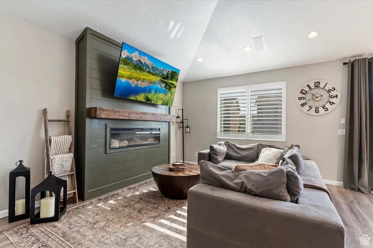 Living area featuring light wood-type flooring, a fireplace, a textured ceiling, and recessed lighting