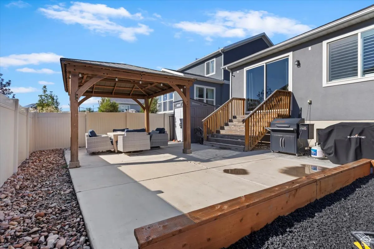 Fenced backyard with a patio area, an outdoor living space, a gazebo, a grill, and a shed