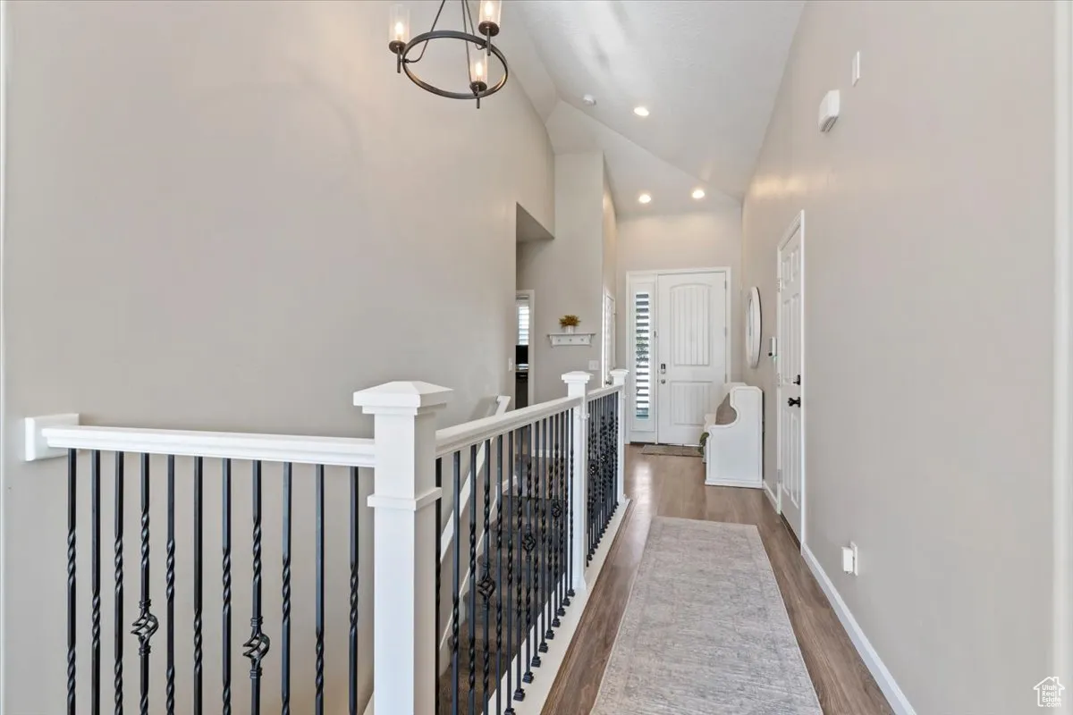Hallway featuring high vaulted ceiling, an upstairs landing, wood finished floors, a chandelier, and recessed lighting