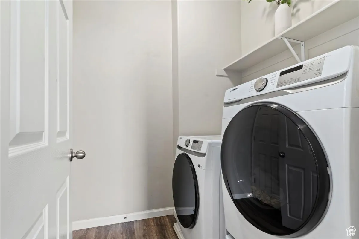 Laundry room featuring independent washer and dryer and dark wood-style flooring
