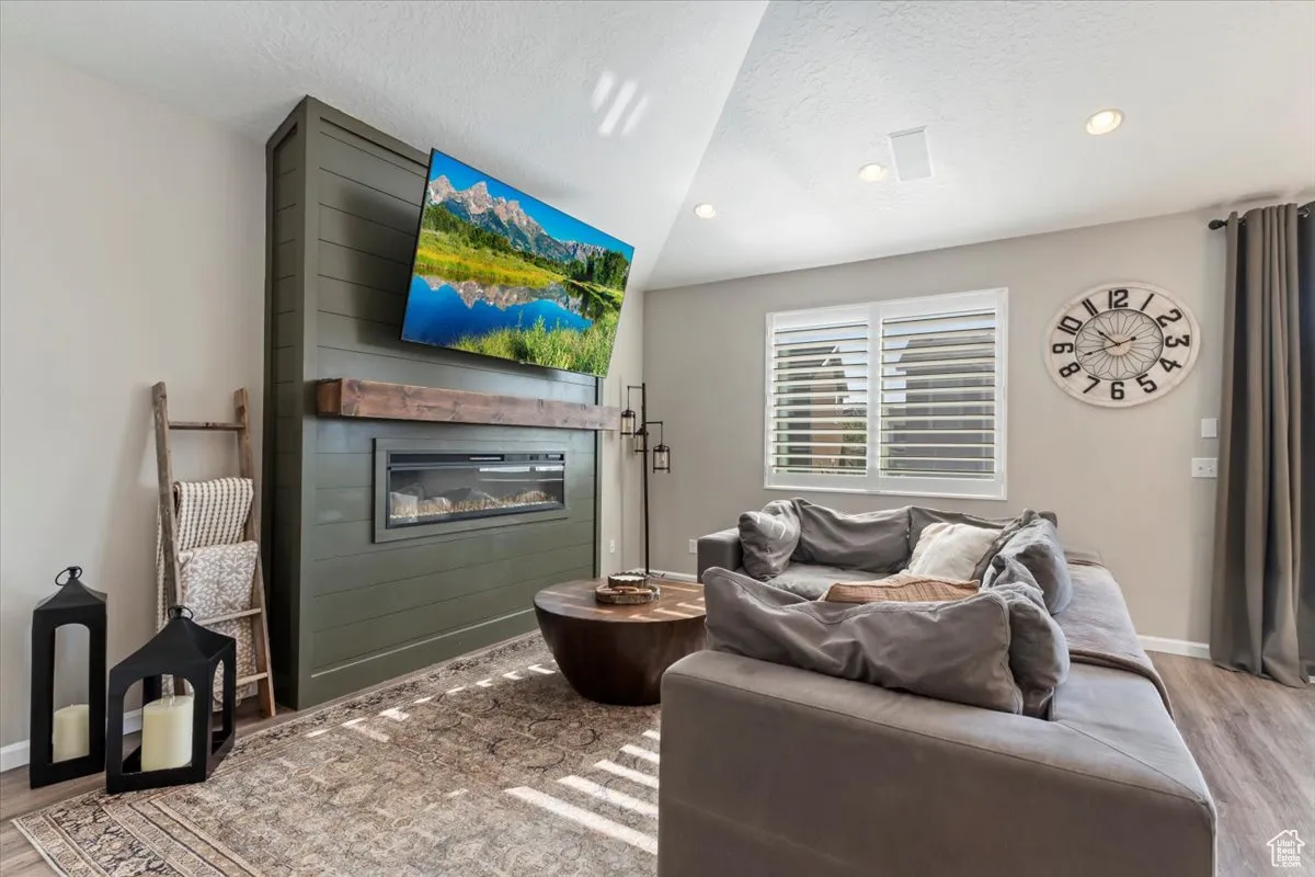 Living room with light wood-style flooring, a textured ceiling, a fireplace, and recessed lighting