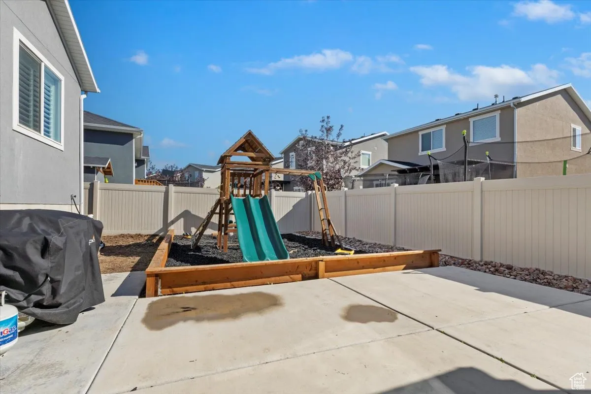 View of playground with a fenced backyard, a patio area, and a residential view