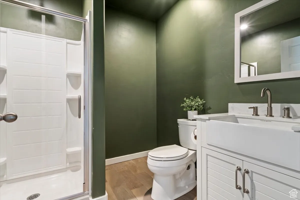 Full bath featuring vanity, a shower stall, and light wood-style flooring
