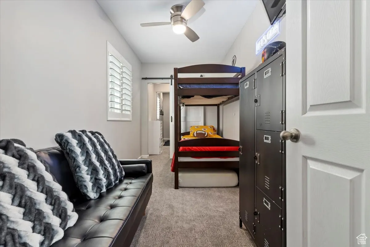 Bedroom with carpet floors, a barn door, and ceiling fan