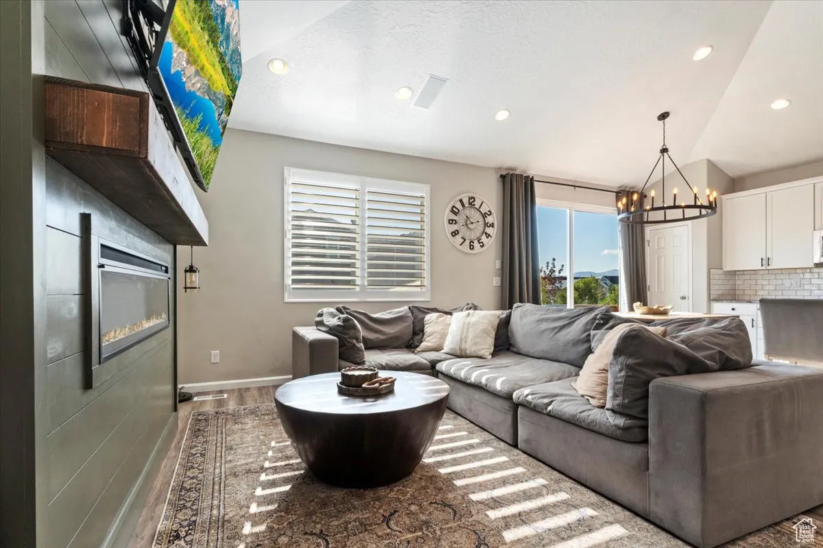 Living area featuring a chandelier, light wood finished floors, recessed lighting, a glass covered fireplace, and a textured ceiling