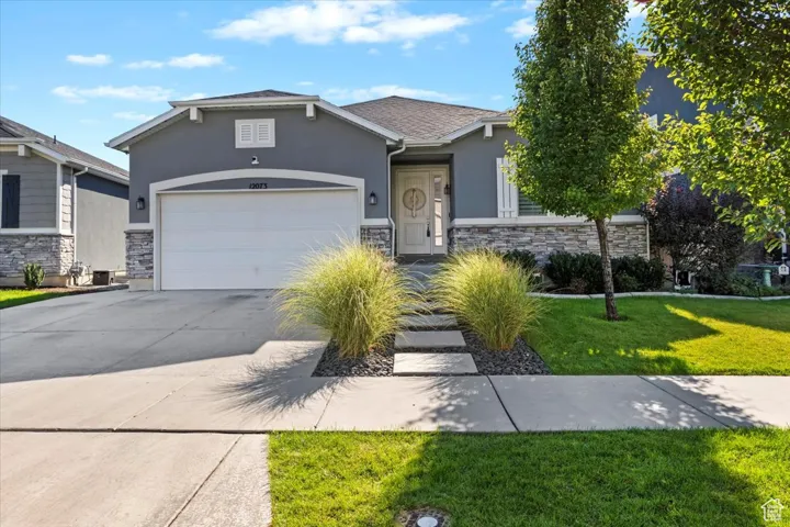 View of front facade featuring stone siding, stucco siding, a front lawn, and driveway