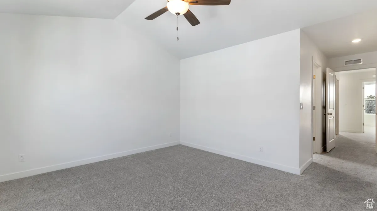 Spare room featuring carpet flooring, a ceiling fan, and vaulted ceiling
