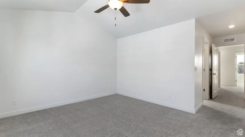 Spare room featuring carpet flooring, a ceiling fan, and vaulted ceiling