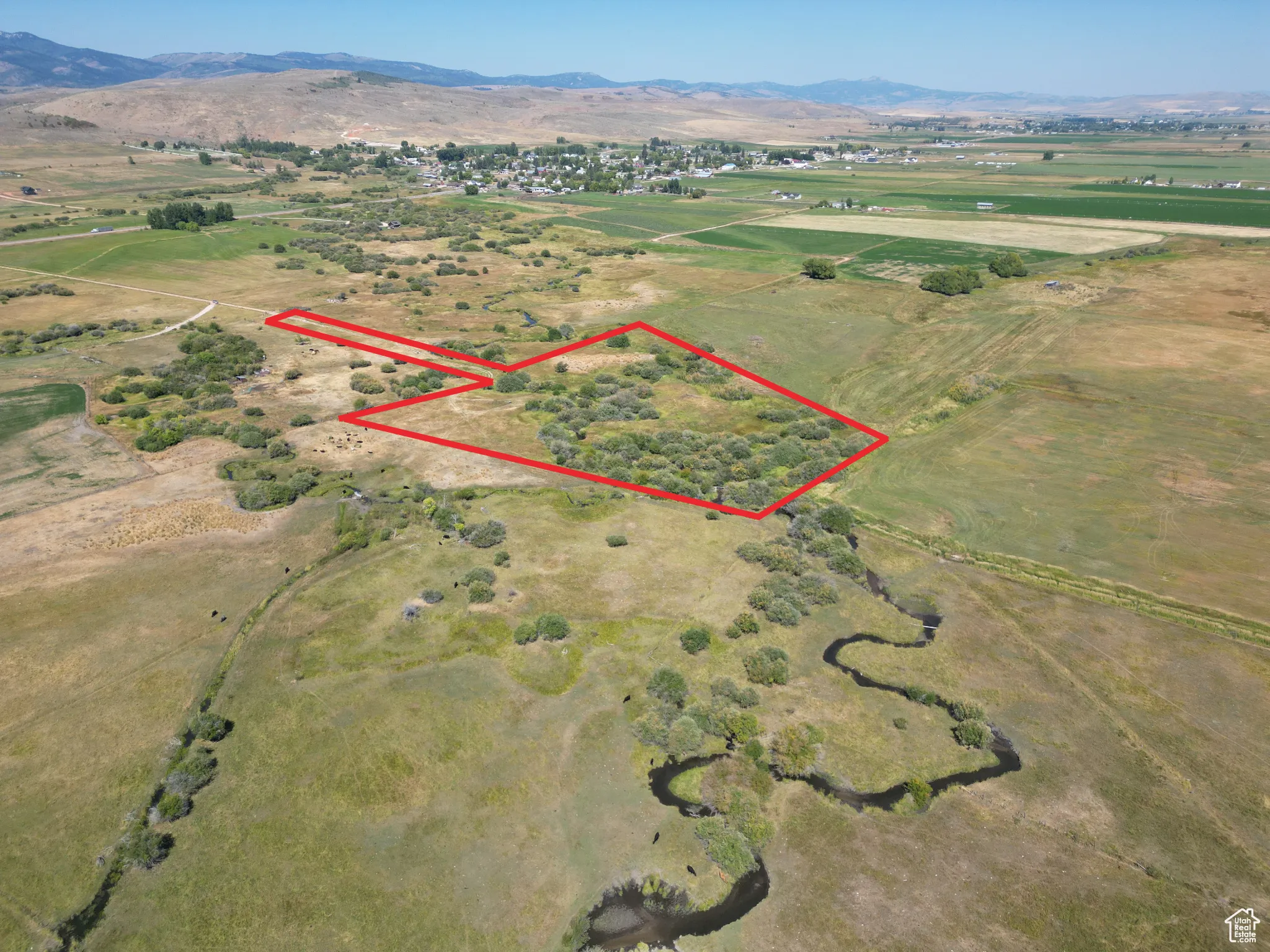 Bloomington 13 acres Aerial view of property and surrounding area with rural landscape, property parcel outlined, and a mountain backdrop