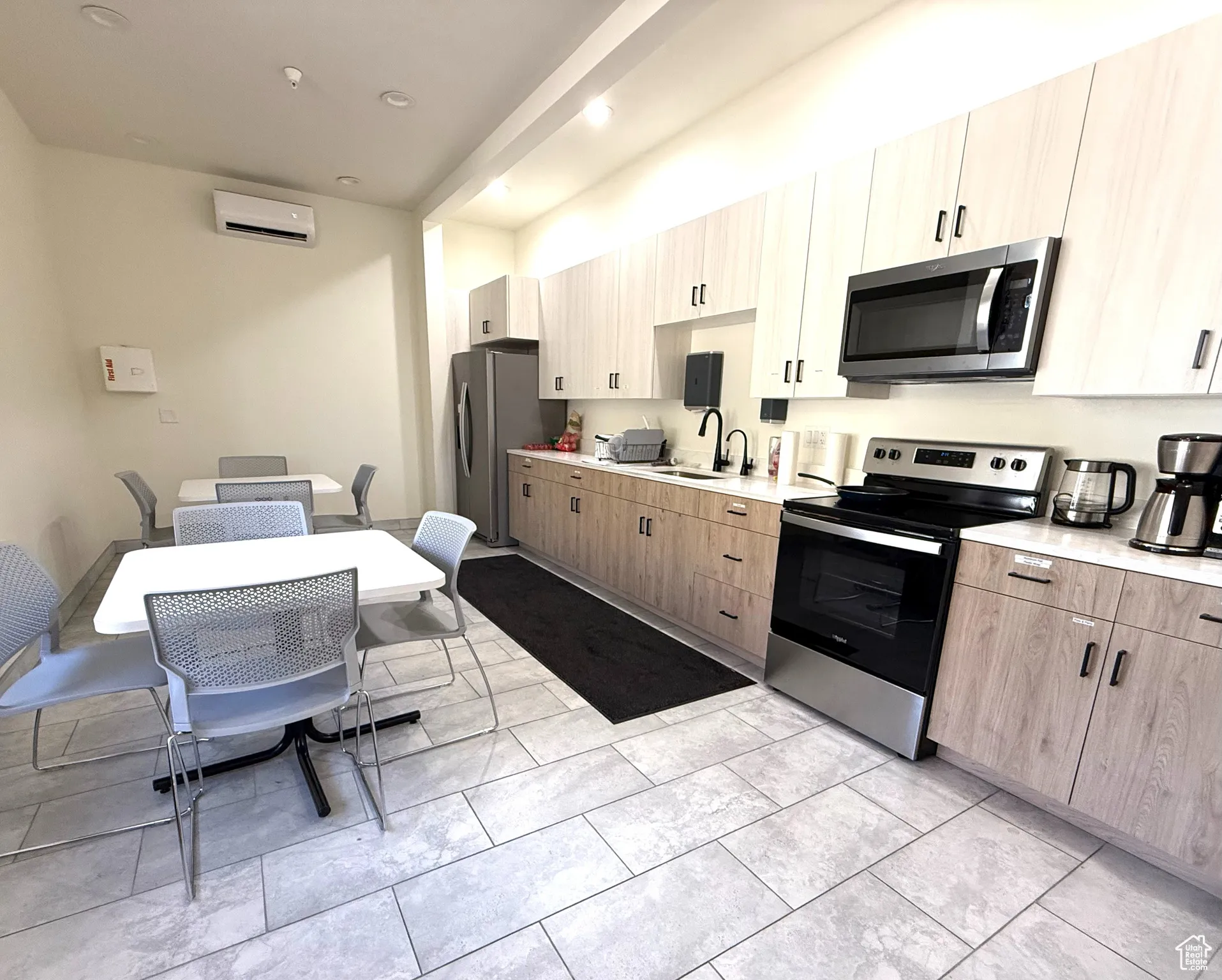 Kitchen featuring appliances with stainless steel finishes, light brown cabinets, recessed lighting, modern cabinets, and a wall unit AC