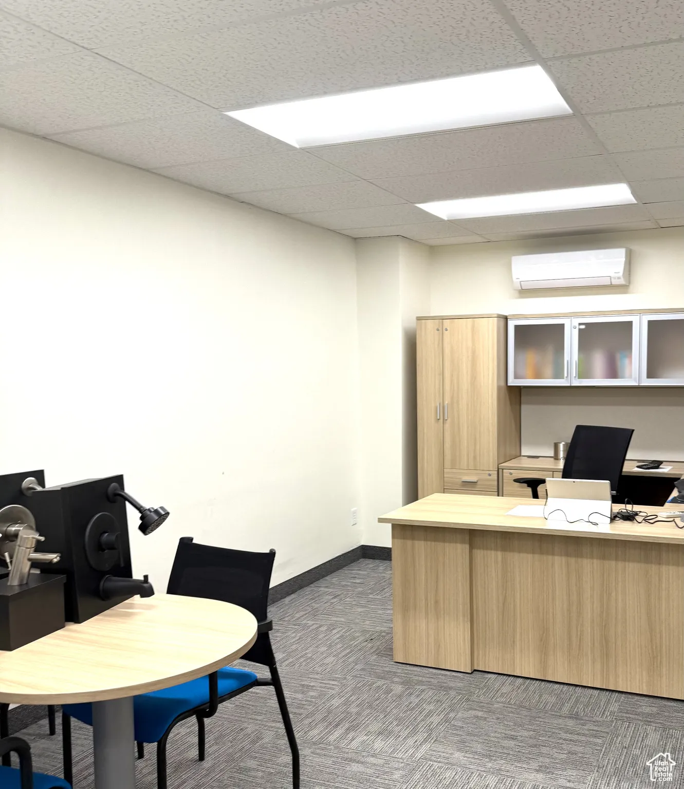 Office area featuring a paneled ceiling and an AC wall unit