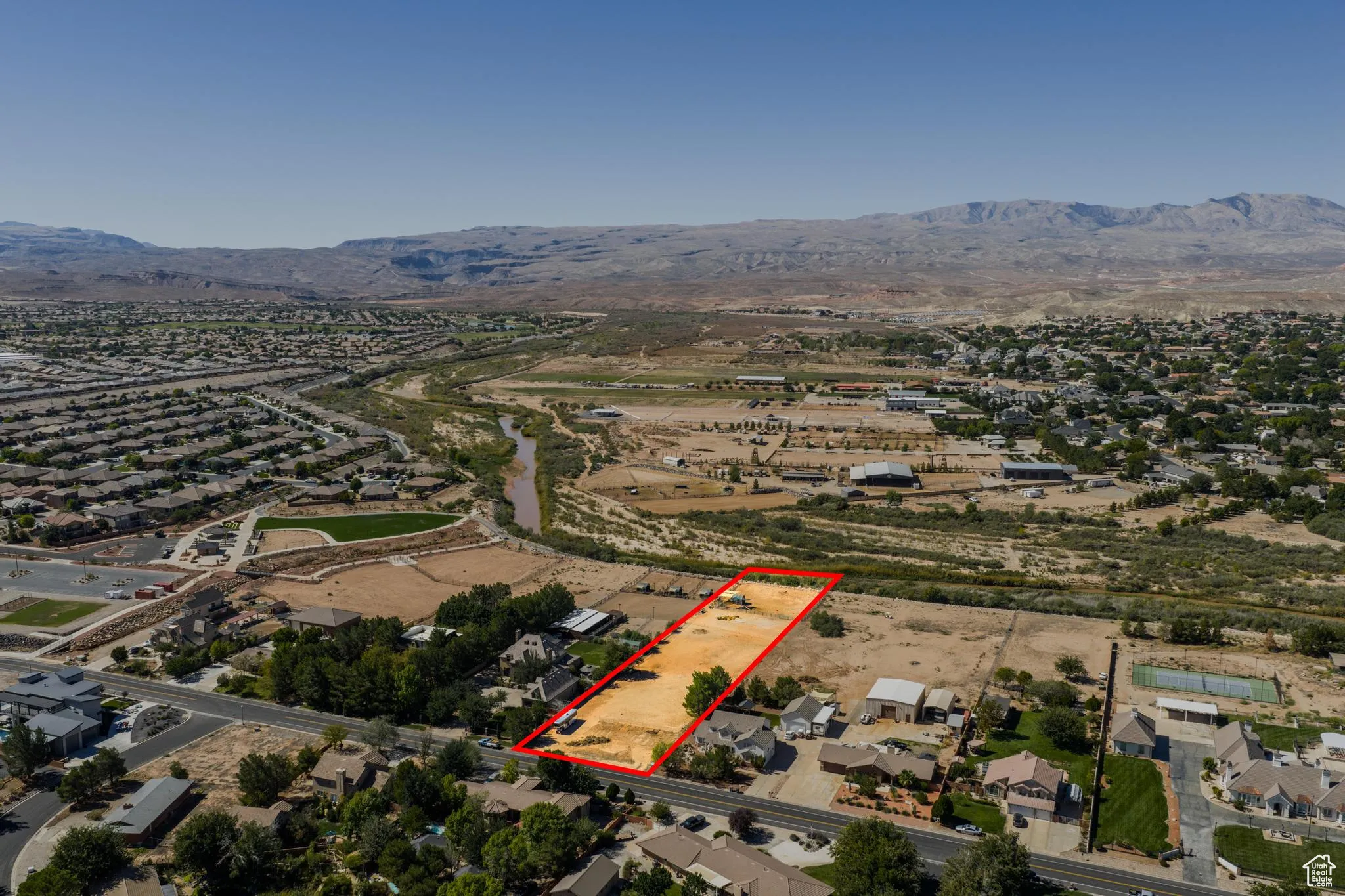 Aerial overview of property's location with nearby suburban area, mountains, and property boundaries highlighted