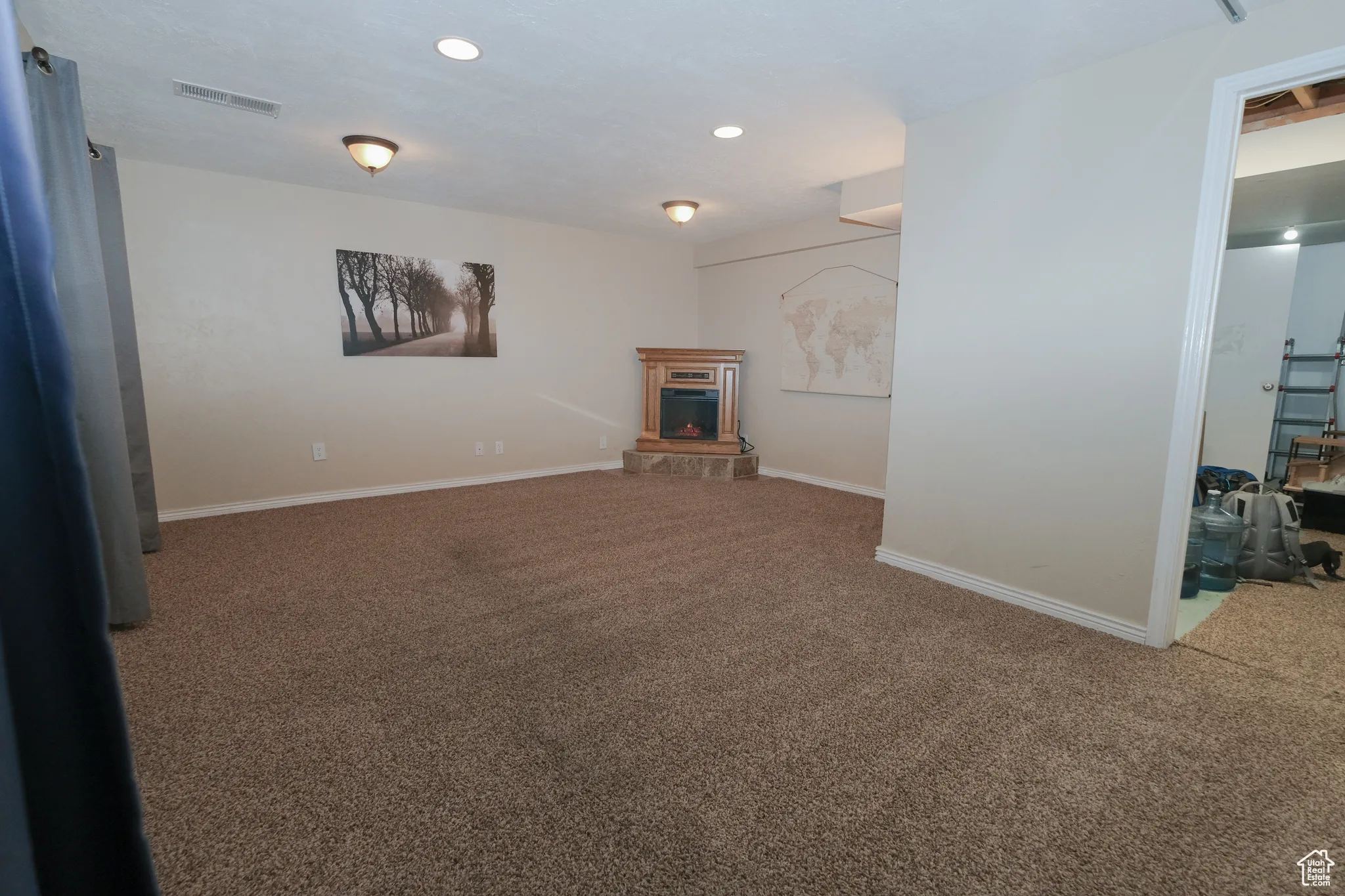 Basement family room with  fireplace, raised hearth, and recessed lighting along with blackout drapes for a private theater atmosphere.