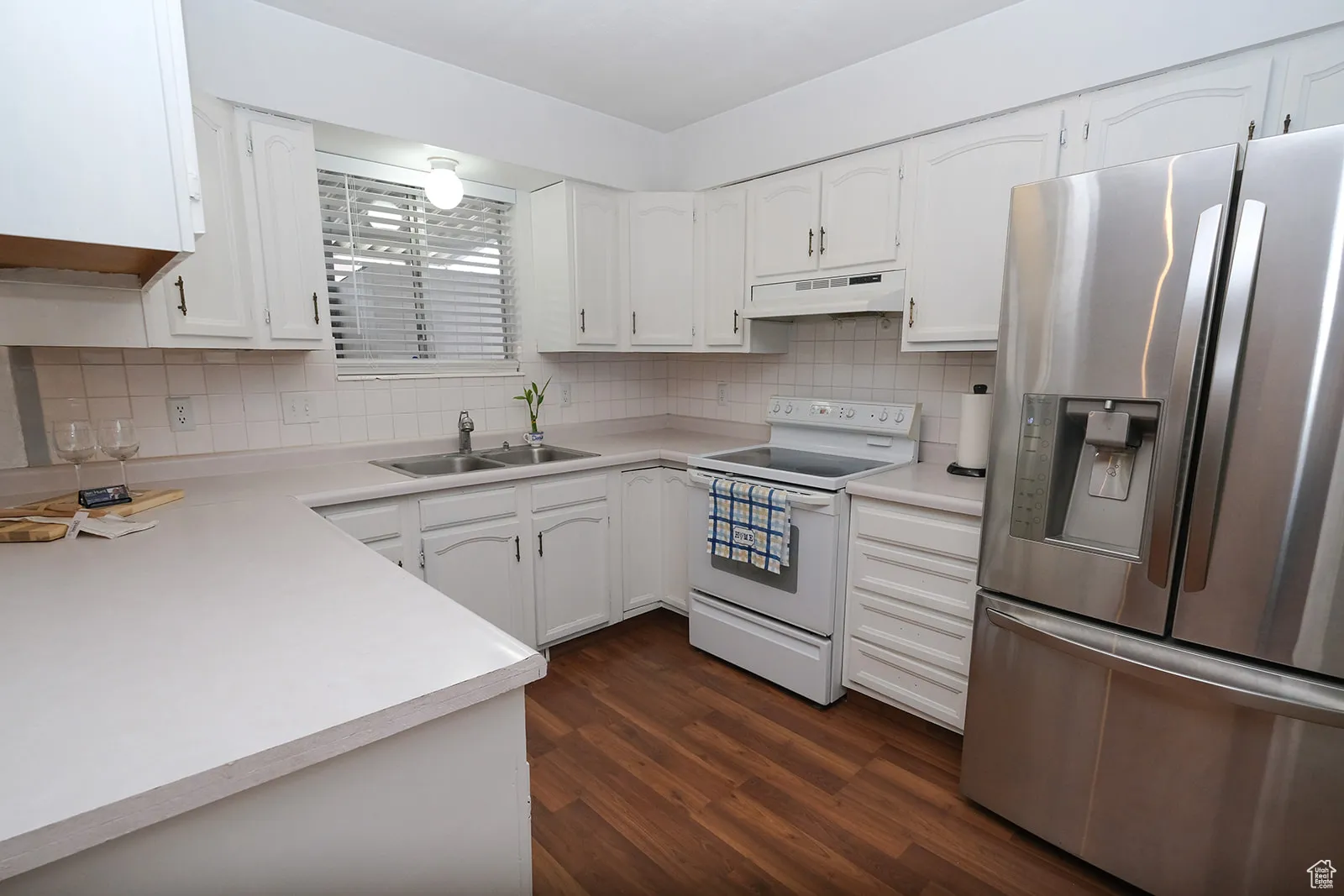 Kitchen featuring stainless steel fridge, white cabinets.