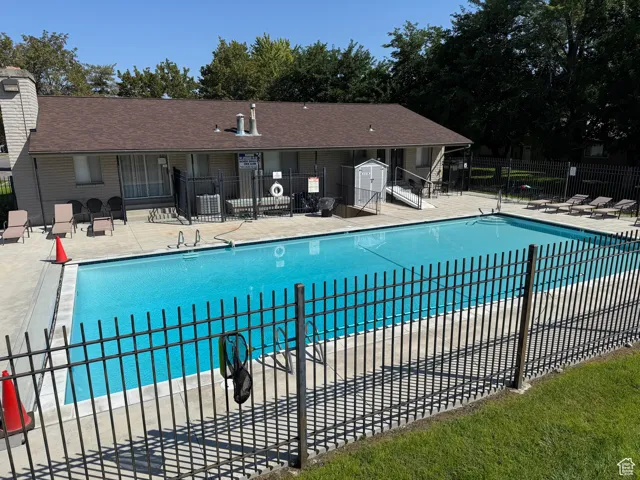 Community pool with a patio area, fenced and adjacent to playground.