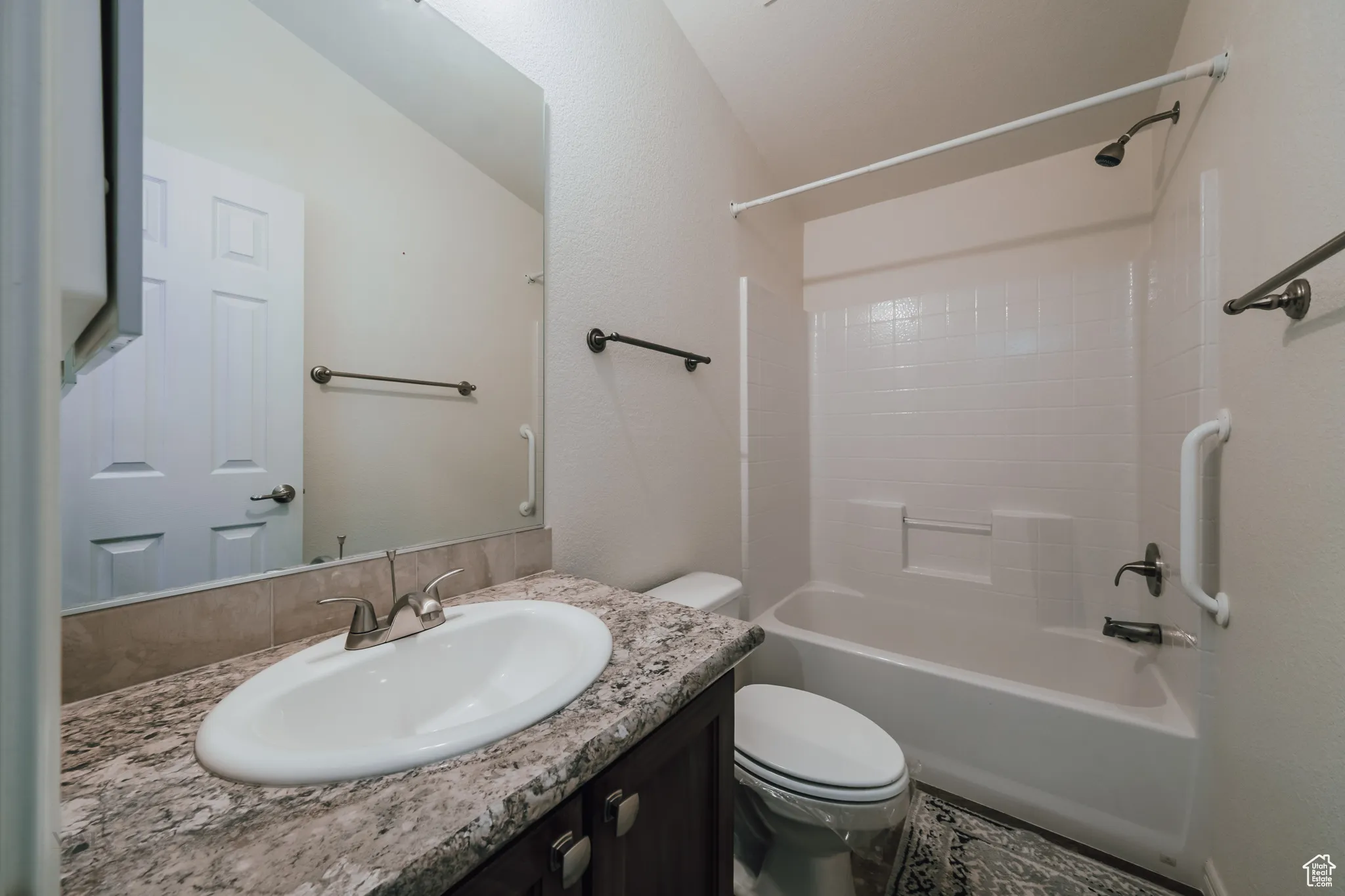 Bathroom featuring vanity, bathing tub / shower combination, and a textured wall