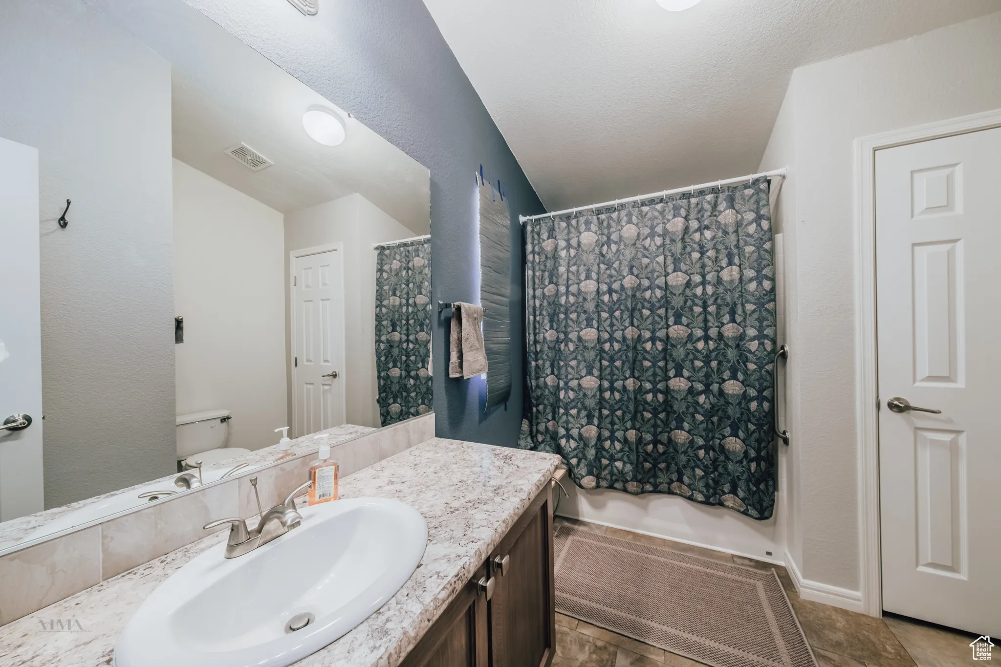 Bathroom with vanity, a textured wall, and a textured ceiling
