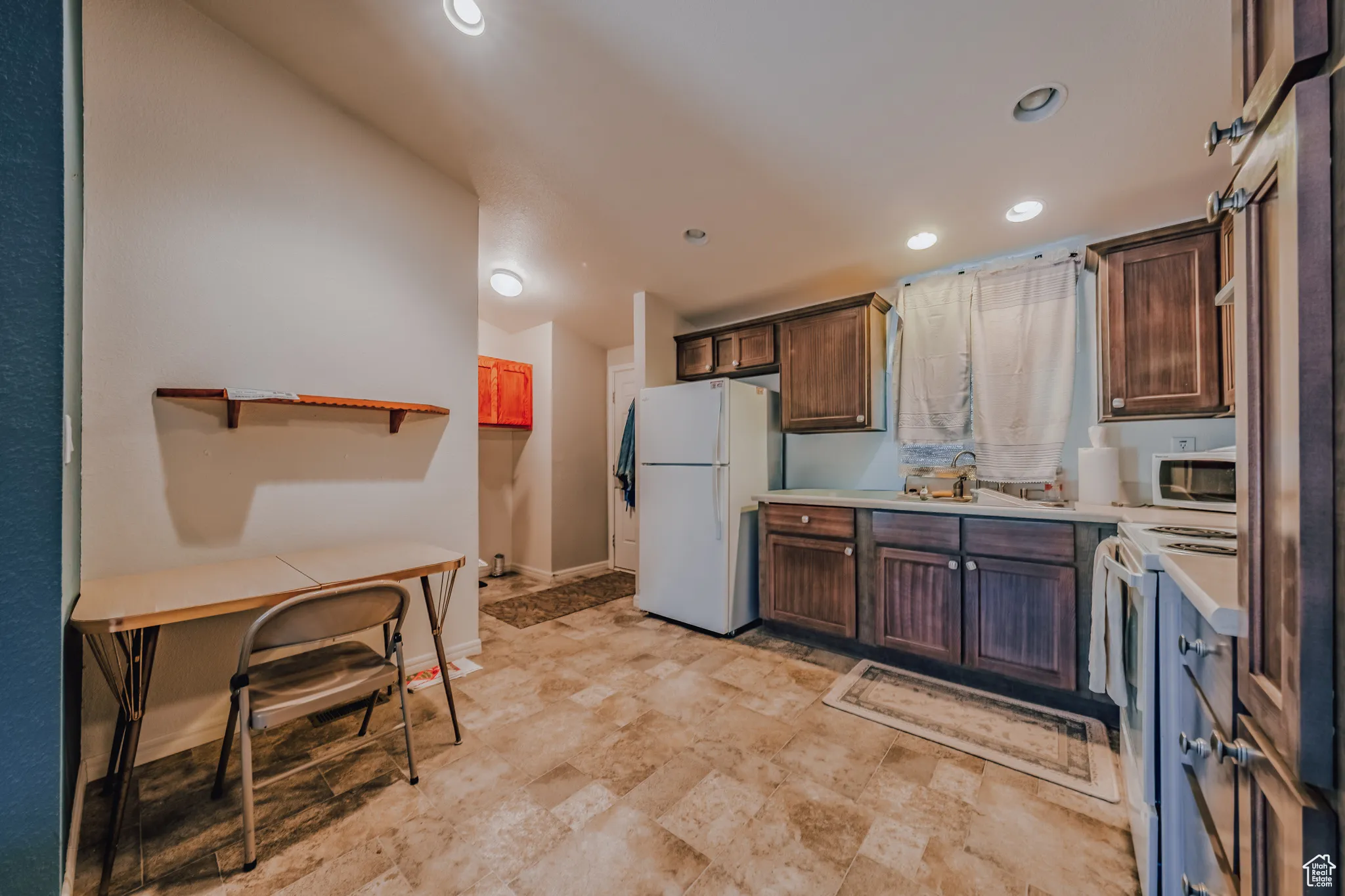 Kitchen featuring light countertops, white appliances, recessed lighting, lofted ceiling, and dark brown cabinets