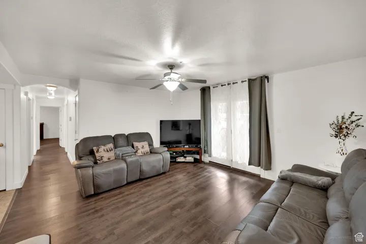 Living area featuring wood finished floors, a textured ceiling, arched walkways, and a ceiling fan