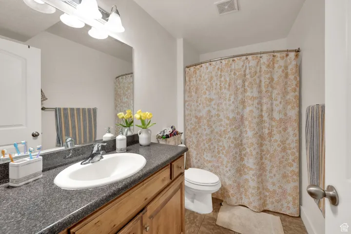 Full bath featuring vanity, light tile patterned floors, and a shower with shower curtain
