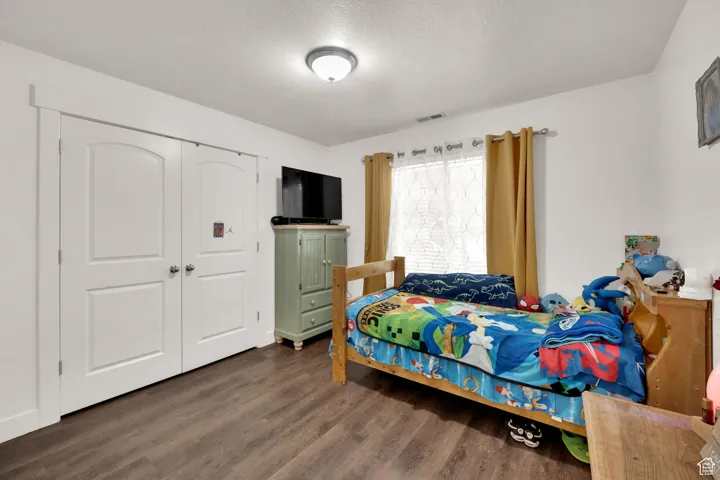 Bedroom featuring a textured ceiling, dark wood-type flooring, and a closet