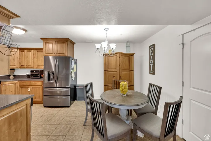 Dining space featuring a chandelier, light tile patterned floors, and a textured ceiling