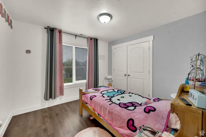 Bedroom with dark wood-style floors, a closet, and a textured ceiling