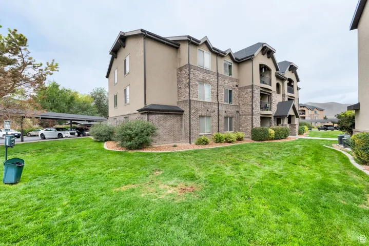 View of property exterior featuring a yard, stucco siding, and stone siding