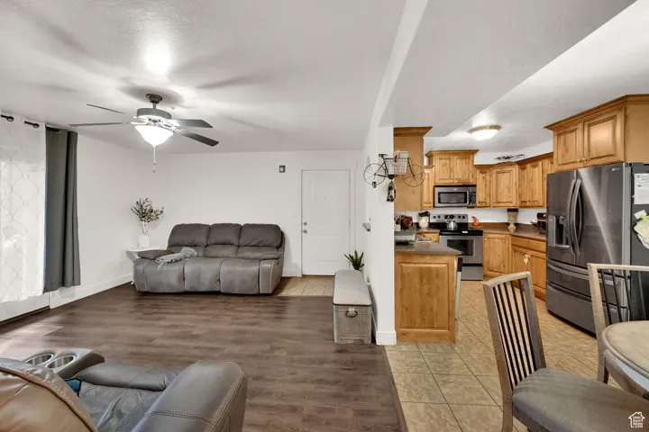 Living room featuring a textured ceiling, a ceiling fan, and light wood-style floors