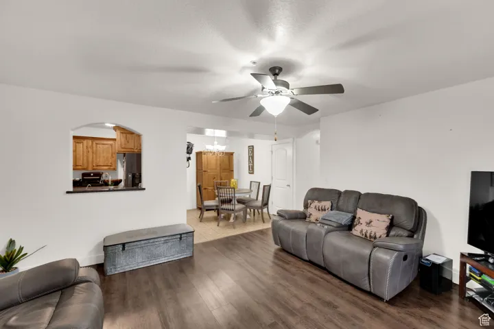 Living area featuring dark wood finished floors, a textured ceiling, ceiling fan, and a chandelier