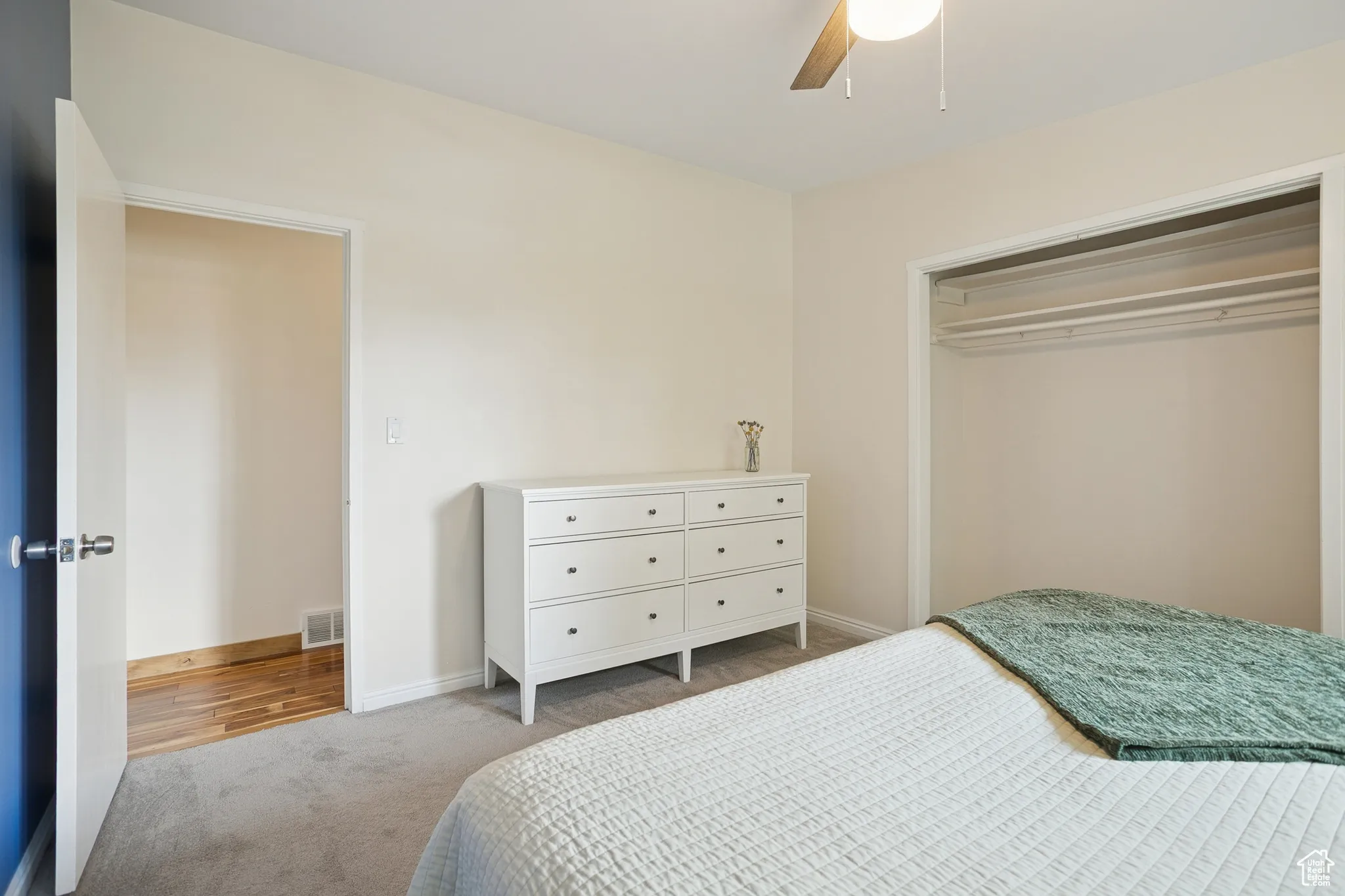 Carpeted bedroom featuring a ceiling fan and a closet