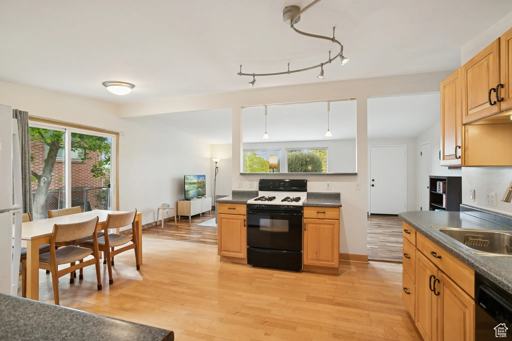 Kitchen featuring range with gas cooktop, dark countertops, light wood-style flooring, and dishwasher