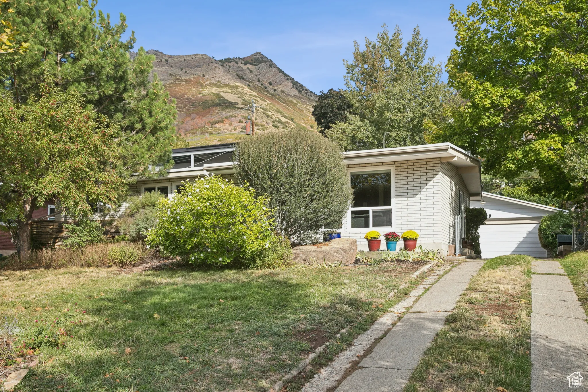 View of front facade featuring brick siding, a front lawn, and a mountain view